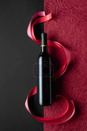 Foto de Bottle of red wine with red and pink satin ribbons. Top view. - Imagen libre de derechos