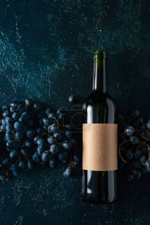 Téléchargez les photos : Bouteille de vin rouge et raisins sur fond bleu vintage. Sur une vieille étiquette vide. Espace de copie. - en image libre de droit