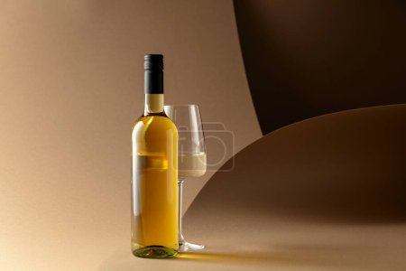 Téléchargez les photos : Bouteille et verre de vin blanc sur fond beige. - en image libre de droit