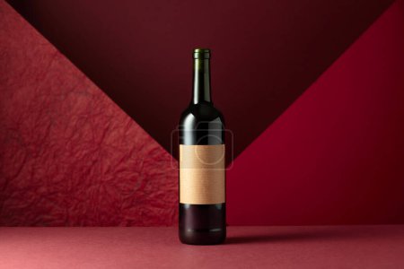 Photo for Bottle of red wine on a red background. On a bottle old empty label. Copy space for your text. - Royalty Free Image