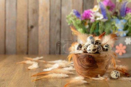 Photo for Easter composition with quail eggs, feathers, and spring flowers on a old wooden table. Copy space. - Royalty Free Image