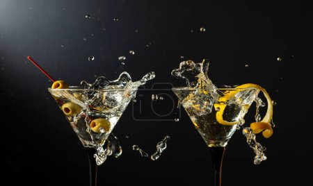 Téléchargez les photos : Cocktail martini sec classique aux olives vertes et écorce de citron sur fond noir. Martini aux éclaboussures. Espace libre pour votre texte. - en image libre de droit