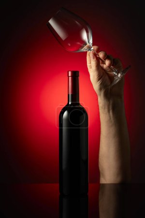 Téléchargez les photos : Bouteille non ouverte de vin rouge et verres à vin mains. Concept du thème du vin. - en image libre de droit