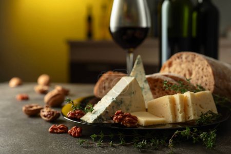Téléchargez les photos : Fromage, pain, vin rouge et noix sur une table de cuisine. Snacks méditerranéens traditionnels. - en image libre de droit