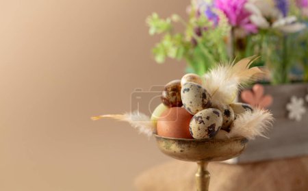 Téléchargez les photos : Composition pascale avec œufs, plumes et fleurs printanières sur fond beige. Concentration sélective. - en image libre de droit