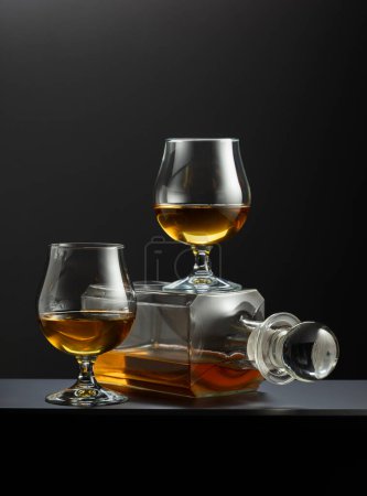 Photo for Old decanter and glasses with whiskey, cognac or brandy on a black background. - Royalty Free Image
