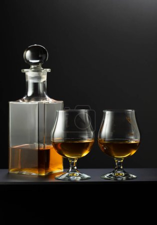 Photo for Old decanter and glasses with whiskey, cognac or brandy on a black background. - Royalty Free Image