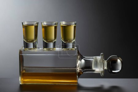Foto de Decantador viejo y vasos con bebida alcohólica fuerte sobre un fondo negro. - Imagen libre de derechos