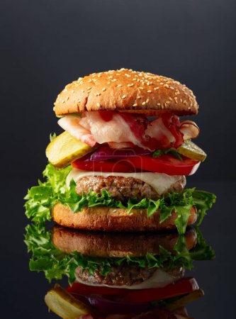 Téléchargez les photos : Hamburger frais et savoureux sur fond noir réfléchissant. - en image libre de droit