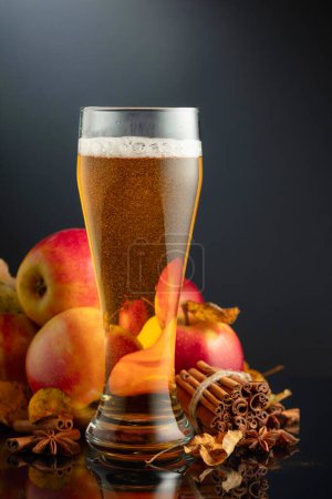 Foto de Sidra de manzana en vidrio alto. Bebida fresca con manzanas, canela y anís sobre un fondo negro. - Imagen libre de derechos