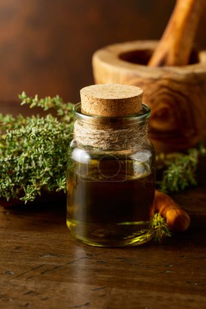 Téléchargez les photos : Bouteille d'huile essentielle de thym au thym frais sur une vieille table en bois. - en image libre de droit