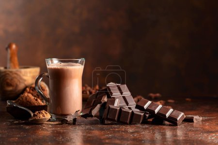 Foto de Pedazos de chocolate amargo y vaso de bebida de cacao en una mesa vintage marrón. Copiar espacio. - Imagen libre de derechos
