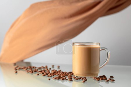 Photo for Coffee with cream on a glass table. In the background waving beige curtain. - Royalty Free Image