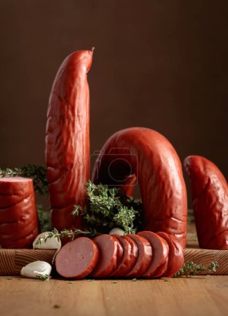 Photo for Smoked sausage with thyme and garlic on a wooden table. Copy space. - Royalty Free Image