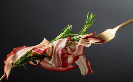 Photo for Dry-cured pork belly bacon with rosemary on a black background. Copy space. - Royalty Free Image