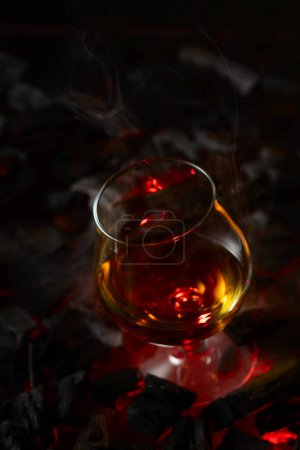 Photo for Snifter of brandy on a burning charcoal. Concept of hard alcoholic drinks. Copy space. - Royalty Free Image