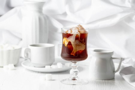 Téléchargez les photos : Café glacé avec crème et tasse de café noir sur une table en bois blanc. - en image libre de droit
