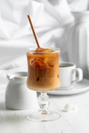 Téléchargez les photos : Café glacé avec crème et tasse de café noir sur une table en bois blanc. - en image libre de droit