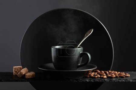 Foto de Taza de café negro con granos de café y azúcar morena. Café con ingredientes sobre fondo negro. - Imagen libre de derechos