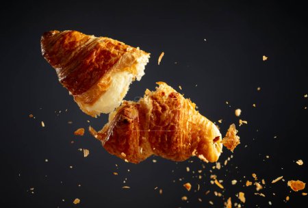 Foto de Croissant recién horneado en el aire sobre un fondo negro. - Imagen libre de derechos