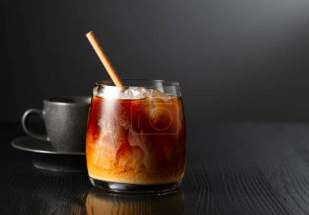 Téléchargez les photos : Café glacé avec crème et tasse de café noir sur une table en bois noir. Espace de copie. - en image libre de droit