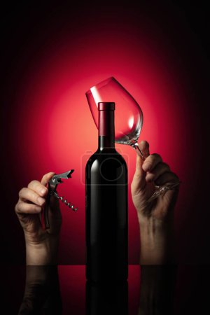 Téléchargez les photos : Bouteille non ouverte de vin rouge et les mains avec tire-bouchon et verre à vin. Concept du thème du vin. - en image libre de droit