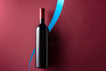 Téléchargez les photos : Bouteille de vin rouge sur fond rouge foncé. Vue de dessus. Espace de copie. - en image libre de droit