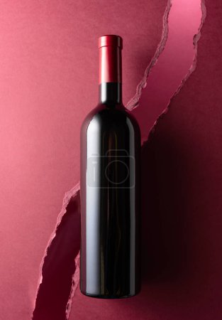 Téléchargez les photos : Bouteille de vin rouge sur fond rouge foncé. Vue du dessus. - en image libre de droit