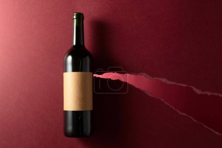 Photo for Bottle of red wine with old empty label on a dark red background. Top view. Copy space. - Royalty Free Image