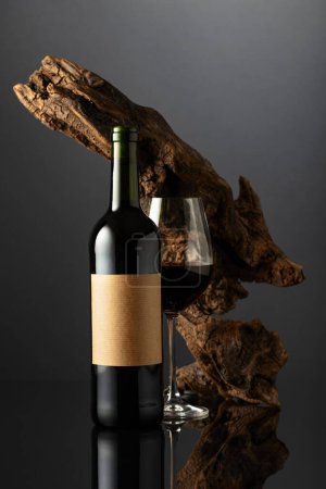 Photo for Bottle with old empty label and glass of red wine. In the background old weathered snag. Concept of expensive wine. - Royalty Free Image