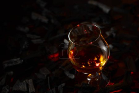 Téléchargez les photos : Un soupçon de brandy sur un charbon en feu. Concept de boissons alcoolisées dures. Espace de copie. - en image libre de droit