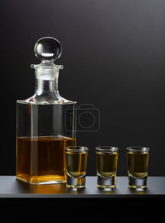 Photo for Old decanter and glasses with strong alcoholic drink on a black background. - Royalty Free Image