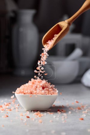Photo for Himalayan pink salt in crystals is poured into a small white bowl. - Royalty Free Image