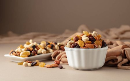 Photo for The mix of various nuts and raisins in a white bowl on a beige background. - Royalty Free Image