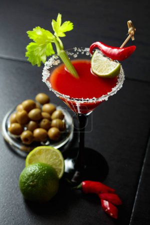 Téléchargez les photos : Cocktail Bloody Mary au céleri, citron vert, poivron rouge et olives vertes. Le verre est décoré avec du sel de mer. - en image libre de droit