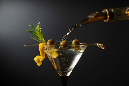 Téléchargez les photos : Cocktail martini sec classique aux olives vertes, écorce de citron et romarin sur fond noir. Espace libre pour votre texte. - en image libre de droit