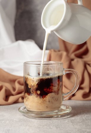 Photo for Pouring creme in a glass cup of coffee. - Royalty Free Image