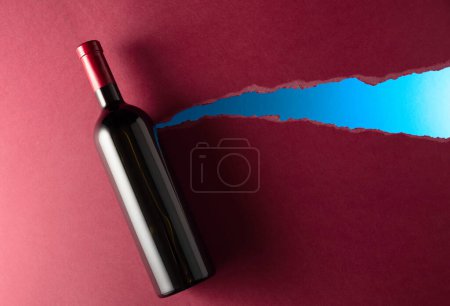 Photo for Bottle of red wine on a dark red background. Top view. Copy space. - Royalty Free Image