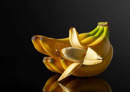 Téléchargez les photos : Bananes mûres sur fond noir réfléchissant. - en image libre de droit