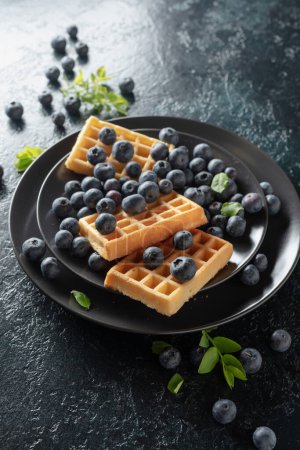 Photo for Belgian waffles with blueberries on a dark blue table. - Royalty Free Image