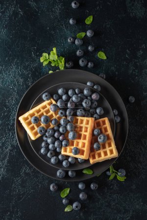 Photo for Belgian waffles with blueberries on a black plate. Top view. - Royalty Free Image