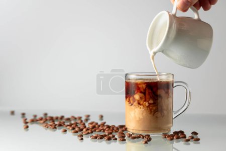 Téléchargez les photos : Café à la crème sur une table en verre. Verser le lait dans le café noir. - en image libre de droit