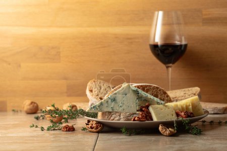 Photo for Cheese, bread, red wine, and walnuts on a kitchen table. Traditional Mediterranean snacks. Copy space. - Royalty Free Image
