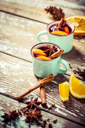 Photo for Mulled wine in rustic mugs with spices and citrus fruit on wooden background - Royalty Free Image