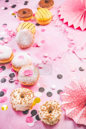 Photo for Traditional Berliner for carnival and party. German Krapfen or donuts with streamers and confetti. Colorful carnival or birthday image - Royalty Free Image