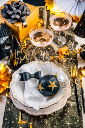 Téléchargez les photos : Nouveau décor de table de l'année avec décoration pour manger et faire la fête en ton noir et doré - en image libre de droit