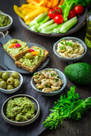 Téléchargez les photos : Snacks végétaliens crus aux légumes frais juteux, trempette avocat, humus et champignons marinés - en image libre de droit