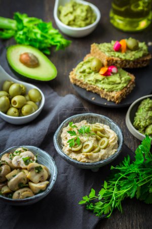 Téléchargez les photos : Snacks végétaliens crus aux légumes frais juteux, trempette avocat, humus et champignons marinés - en image libre de droit