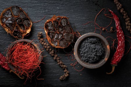 Photo for Organic Fermented Black Garlic with  Himalayan black rock salt  and chili threads - Royalty Free Image