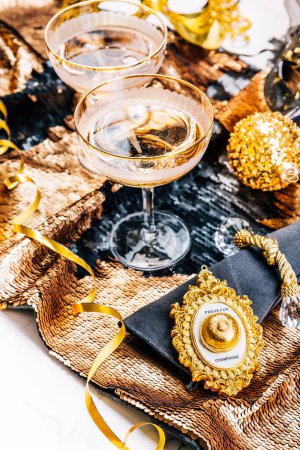 Foto de Dos copas de vino espumoso en la mesa festiva para Año Nuevo, fiesta o carnaval. Botón Bell para champán, en tono dorado - Imagen libre de derechos